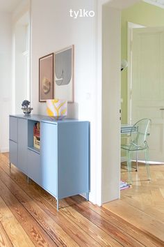 an empty room with wood floors and blue cabinet in the center, next to a white door