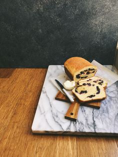 a marble cutting board topped with bread and blueberries on top of a wooden table