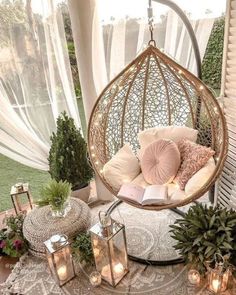 a hammock hanging from the ceiling with pillows and books on it next to potted plants