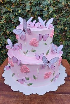 a three tiered cake with pink butterflies on it