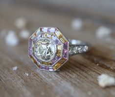 an old diamond ring sitting on top of a wooden table with white and yellow diamonds