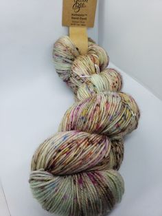 two skeins of yarn sitting on top of a white counter next to a tag