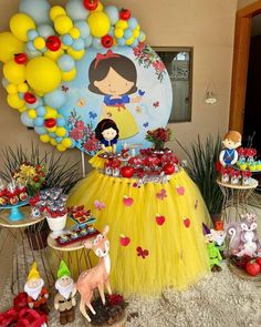 a table topped with cake and cupcakes next to a balloon filled wall in the background