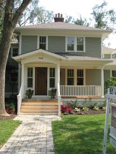 a house that is painted gray and has white trim on the front porch, with steps leading up to it