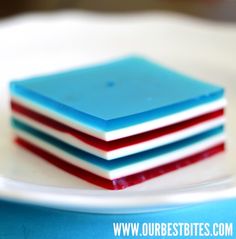 three square pieces of blue, red and white cake on a plate