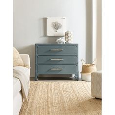 a blue dresser with gold handles in a living room area next to a white couch