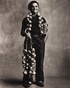 black and white photograph of a man with balls on his neck, standing in front of a gray background