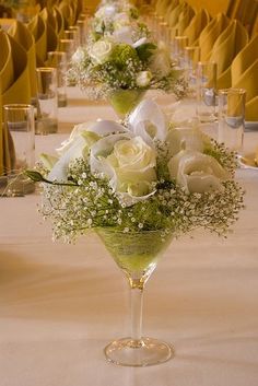 two martini glasses filled with flowers and greenery