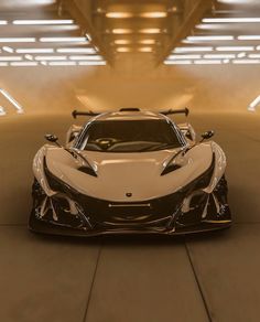 a white and black sports car parked in a parking garage with lights on the ceiling