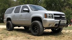 a silver truck parked on top of a grass covered field