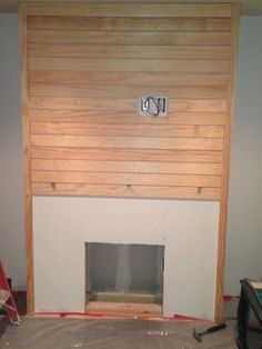 an unfinished fireplace in the middle of a room with wood paneling on the walls