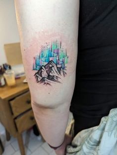 a person with a tattoo on their arm that has mountains and stars in the background