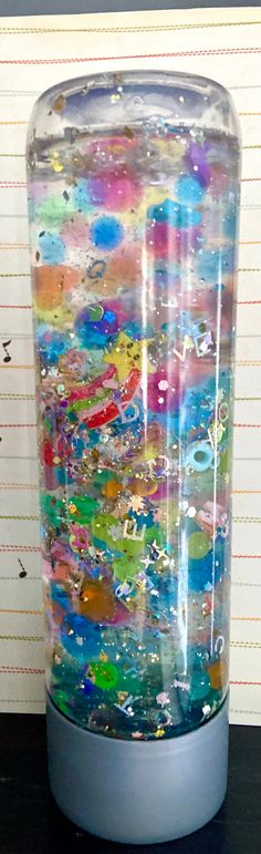 a glass vase filled with lots of different colored liquid and water bubbles on top of a black table