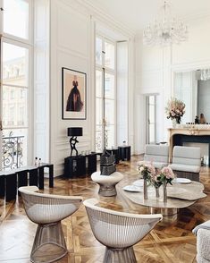 a living room filled with white furniture and lots of windows on top of wooden flooring