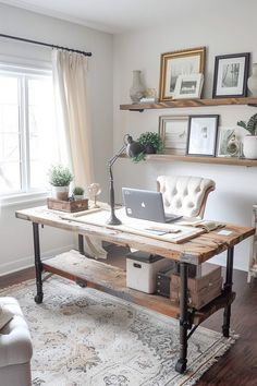 a desk with a laptop on it in front of a window and some pictures above