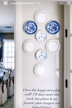 plates are arranged on the wall in front of a dining room table with blue and white china