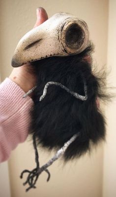 a hand holding a stuffed animal that looks like a bird's head and beak