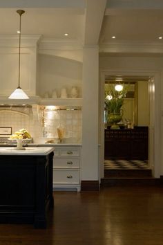 a large kitchen with white cabinets and black island in the center, along with wooden flooring