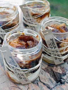 four jars filled with food sitting on top of a wooden table next to each other