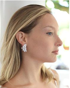 a woman with blonde hair wearing white earrings