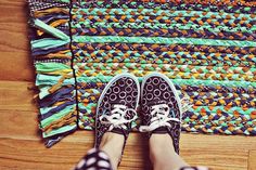 a person standing on top of a wooden floor next to a rug with different colors