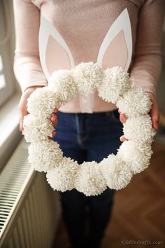 a person holding a white wreath with bunny ears on it