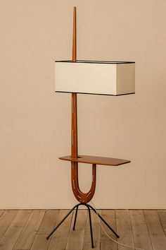 a lamp on a tripod with a wooden base and white shade over the top