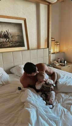 a man holding a baby on top of a bed