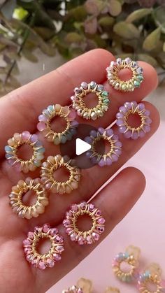 a person is holding several different types of beaded rings in their hand and there are other beads on the table