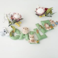 the letters are made out of felt and decorated with stuffed animals, flowers, and leaves