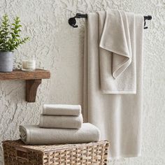 towels are lined up on a shelf next to a basket and towel rack in front of a white wall