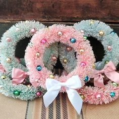 two wreaths with bows are sitting next to each other on top of a table