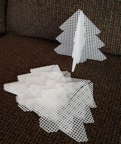 two pieces of white paper cut out to look like christmas trees sitting on a couch