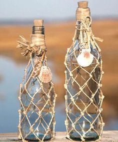 two empty bottles with rope wrapped around them sitting on a wooden table next to a body of water