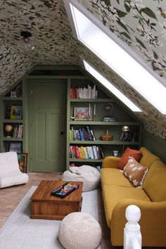 a living room filled with furniture and bookshelves under a slanted skylight