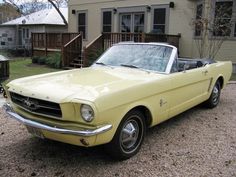 an old yellow mustang parked in front of a house