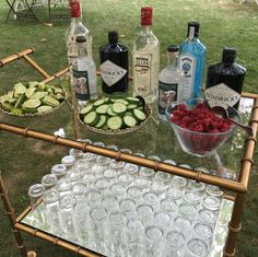 an outdoor table with drinks and cucumbers on it