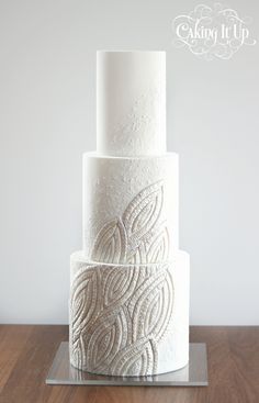 a three tiered white wedding cake sitting on top of a wooden table