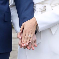 the bride and groom hold hands as they stand close to each other with their wedding rings on their fingers