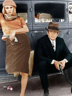 a man sitting next to a woman in front of an old car