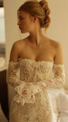 a woman in a wedding dress looking at herself in the mirror with her hands on her hips