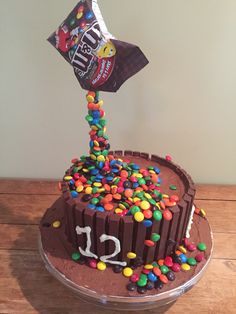 a birthday cake with chocolate frosting and sprinkles on the top that has a candy bar sticking out of it