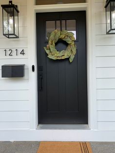 a black front door with a wreath on it and two lights above the door handle