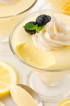 two glasses filled with ice cream and some fruit on the rims next to lemon slices