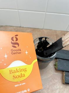 a cup of baking soda next to a wooden spoon with some sort of stick sticking out of it