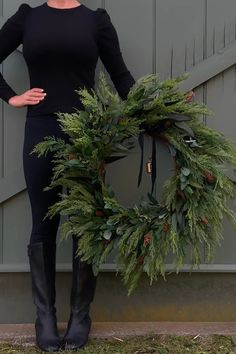 a woman standing next to a door holding a wreath