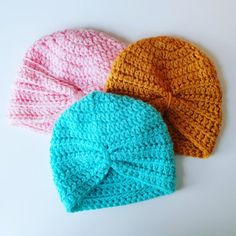 three crocheted hats on a white surface, one has a knot at the top