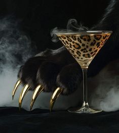 a glass filled with liquid and gold claws