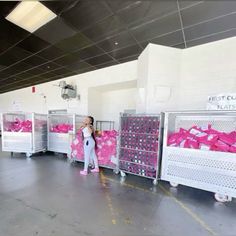 a woman is standing in front of some crates with pink bows on them and she has one hand up to her face