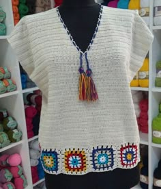 a crocheted sweater with tassels and beads is on display in a store